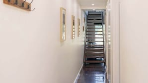 A hallway with a wooden floor, white walls, and a staircase at the end. - Halls Gap Escape Townhouse 6 (Halls Gap)