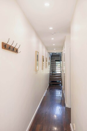 A hallway with a wooden floor, white walls, and a staircase at the end. - Halls Gap Escape Townhouse 6 (Halls Gap)