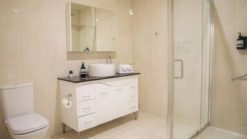 Ein Badezimmer mit Toilette, Waschbecken, Spiegel, Dusche und einem Schrank.