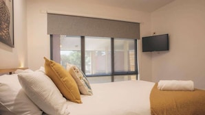 A hotel room with a bed, a television on the wall, and a window with a view. - Halls Gap Escape Townhouse 6 (Halls Gap)