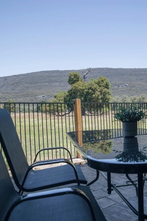Eine Terrasse mit Blick auf ein Wiesfeld und eine Hügelkuppe.