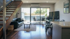 Ein stilvoller Wohnraum mit Treppe, einer Couch, einem Couchtisch, einem Essbereich und einem Fernseher.