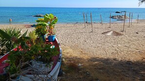 A beach with a row of potted plants, a red and white boat, and a clear blue sky. - The Village Retreat
Live like a local! (Malonas)
