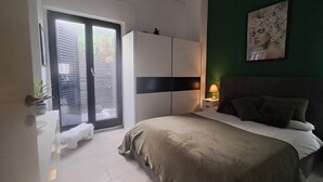 A bedroom with a bed, a wardrobe, a nightstand with a lamp, a green wall, and a window with blinds. - The Village Retreat
Live like a local! (Malonas)
