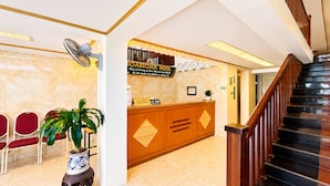 Un'area della reception di un hotel, con una scrivania, un orologio e una scala.