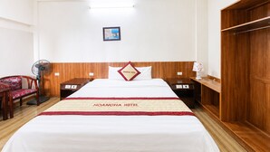 Una camera d'albergo con un letto, comodini, una sedia, un armadio e un quadro appeso al muro.