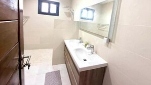 A bathroom with a double sink, a mirror, and a shower. - Bright two-bedroom apartment with a balcony (Dakar)