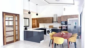 A modern kitchen with a central island, built-in appliances, and a dining area with chairs. - Bright two-bedroom apartment with a balcony (Dakar)