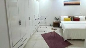 A bedroom with a bed, a nightstand, a dresser, and a wall-mounted TV.