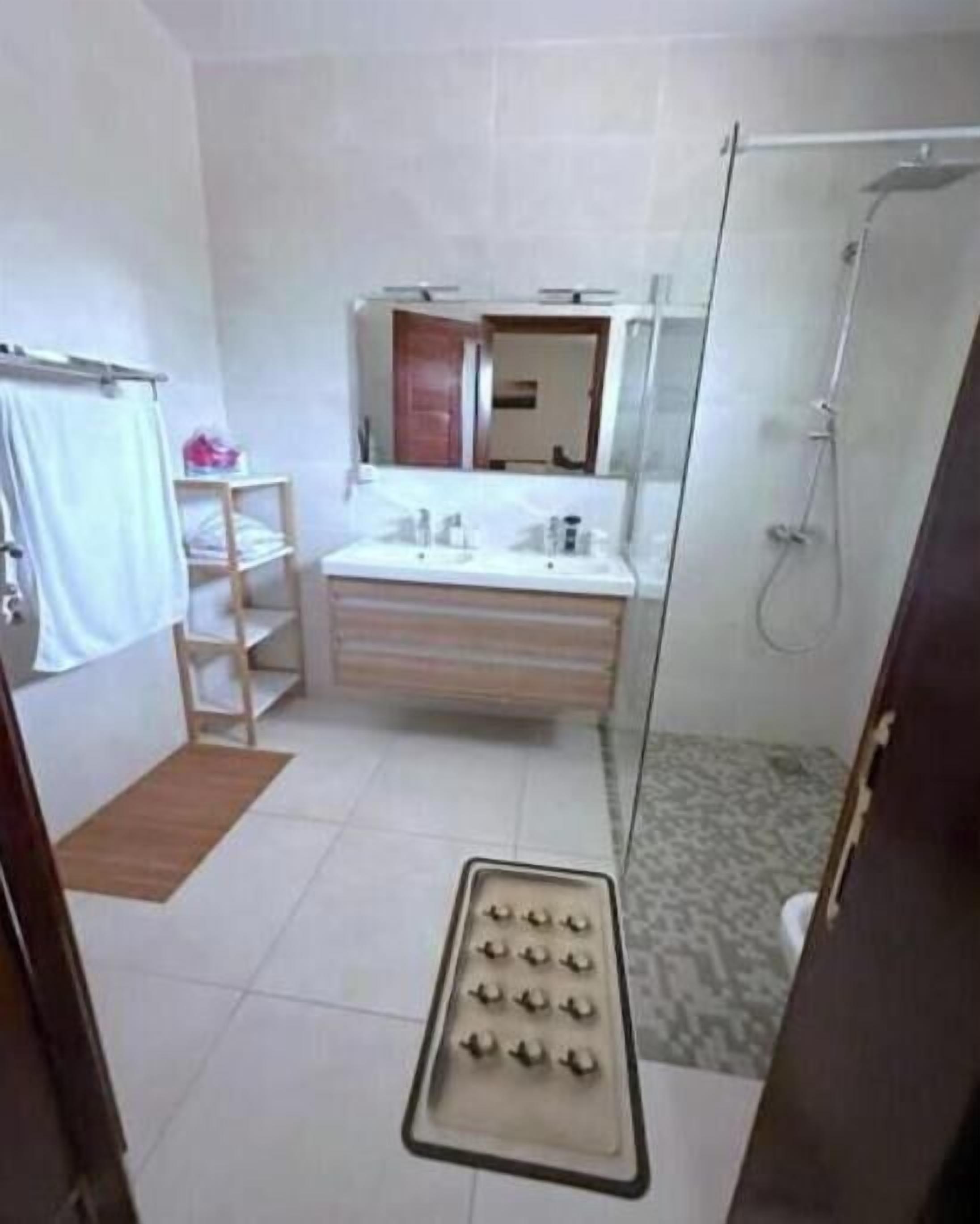 A bathroom with a glass shower enclosure, a sink with toiletries, and a towel rack.