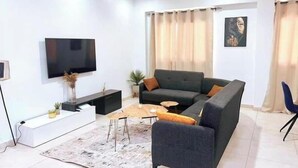A modern living room with a sectional sofa, a flat-screen TV, a coffee table, and a decorative rug.