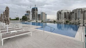 Una piscina en la azotea con vistas a edificios altos, incluido un sitio de construcción.