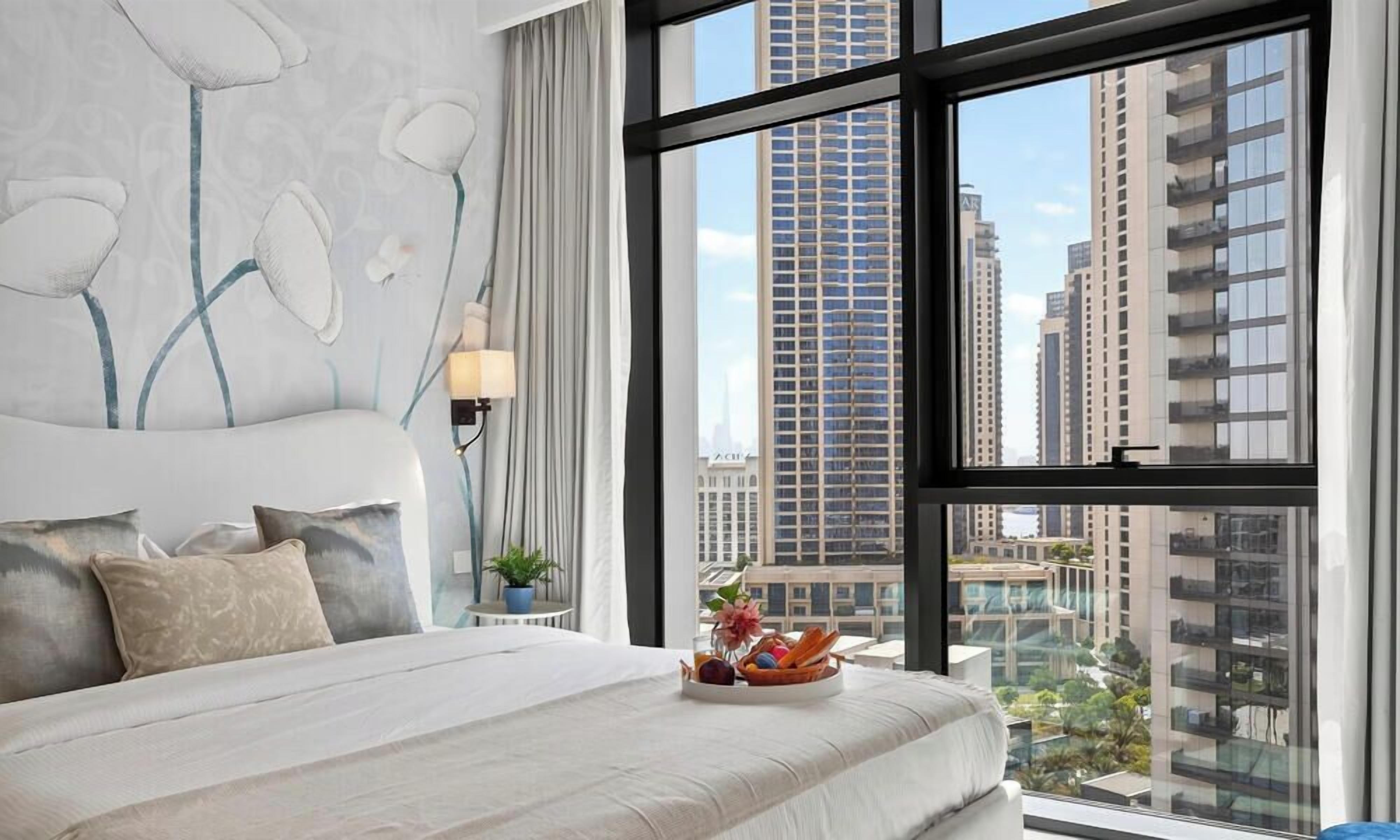 Una camera d'albergo moderna con un letto grande, vista sulla città e una parete decorativa.
