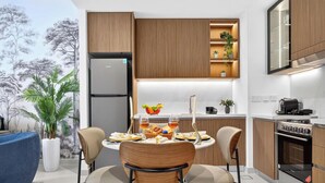 Una cocina moderna con armarios de madera, un horno empotrado y un comedor con una mesa para dos.