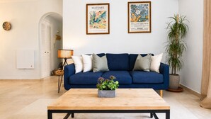 A living room with a blue sofa, a coffee table with a plant, and two framed artworks on the wall. - Coastal Living Near Estepona Marina (Estepona)