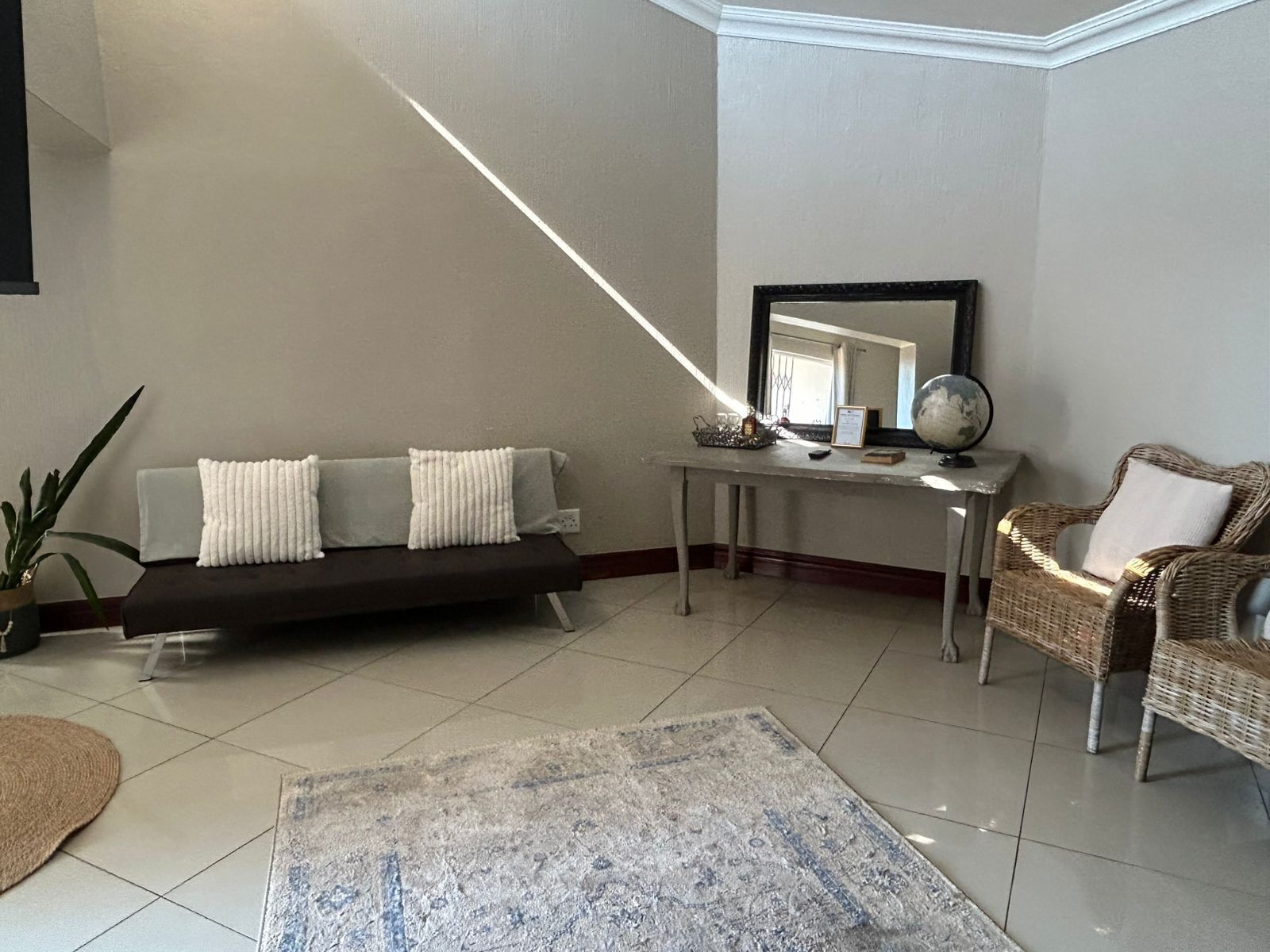 A living room with a sofa, a coffee table, a wicker chair, and a rug.