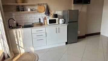 A kitchen with white cabinets, a microwave, a coffee maker, and a refrigerator.