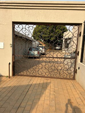 Uma entrada com portão gradeado, com padrão decorativo.