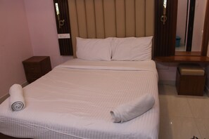 A neatly made bed with a rolled towel, a bedside table, and a nightstand.
