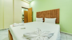 A hotel room with a bed, pillows, a headboard, a towel, and a remote control.