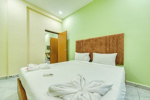 A hotel room with a bed, pillows, a headboard, a towel, and a remote control.