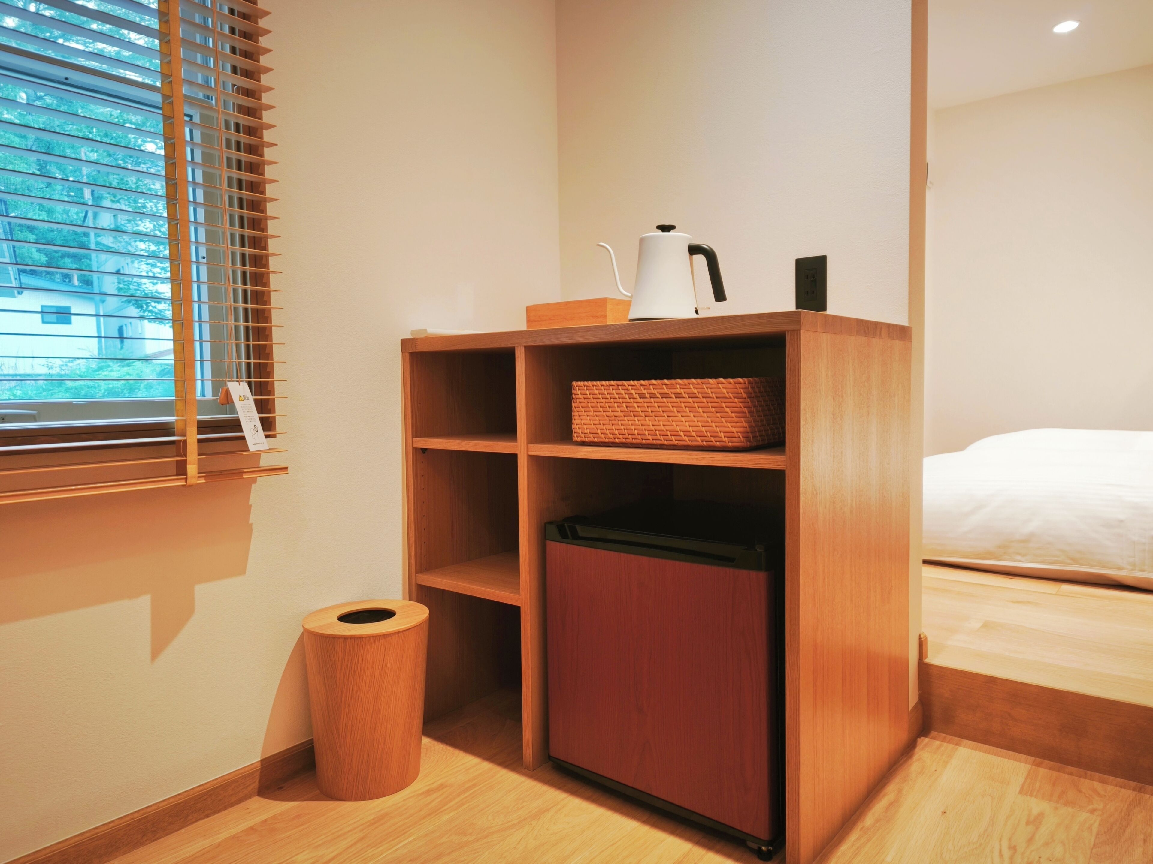 A compact room with a wooden cabinet, a trash bin, and a bed.