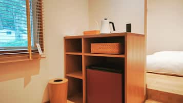 A compact room with a wooden cabinet, a trash bin, and a bed.
