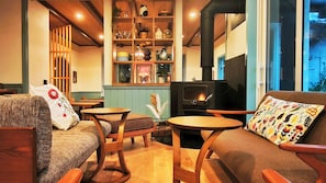 A cozy living room with a fireplace, wooden furniture, and a bookshelf filled with decorative items.