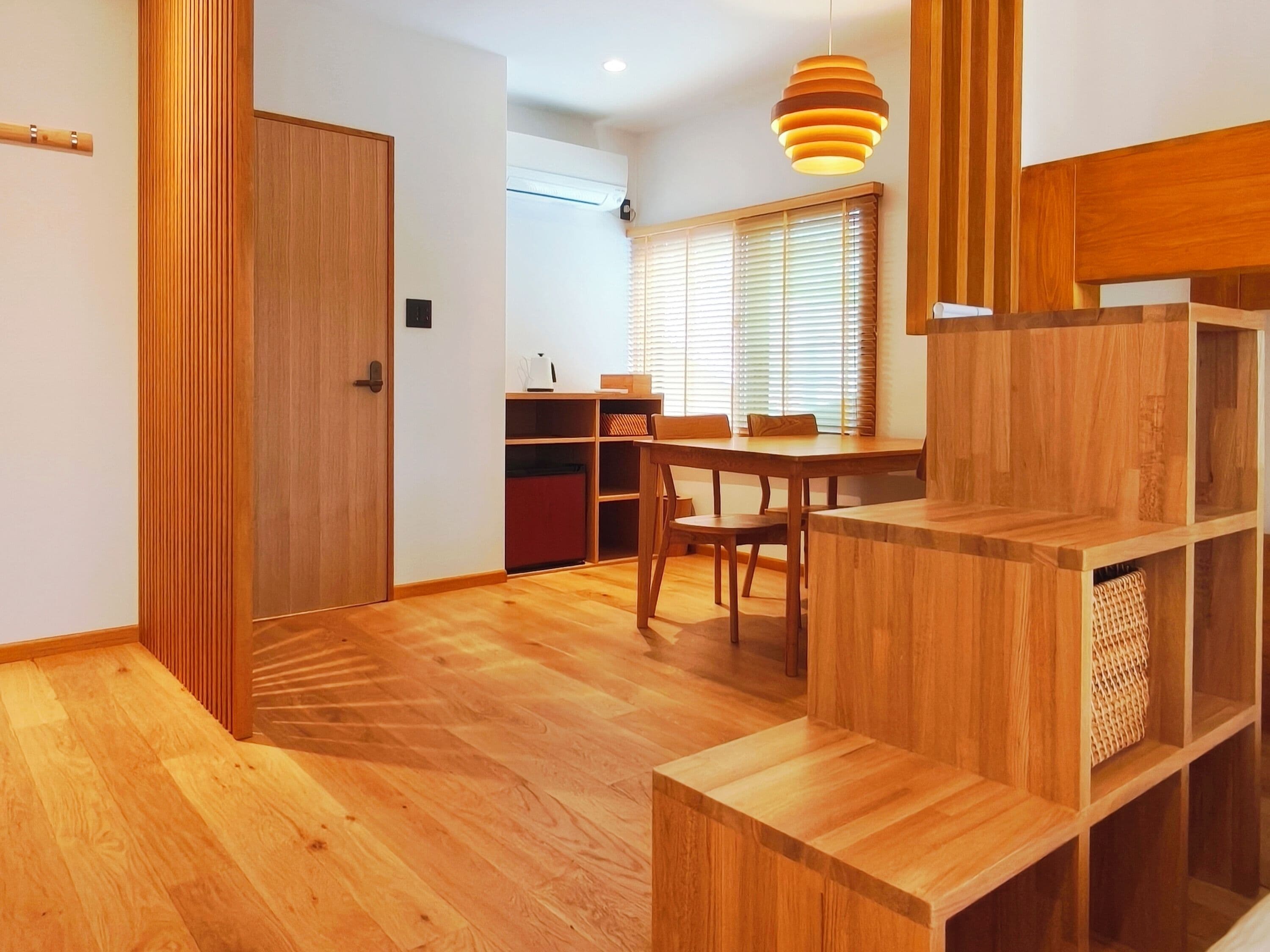 A modern interior with a wooden floor, a dining area with a table and chairs, and a built-in shelving unit.