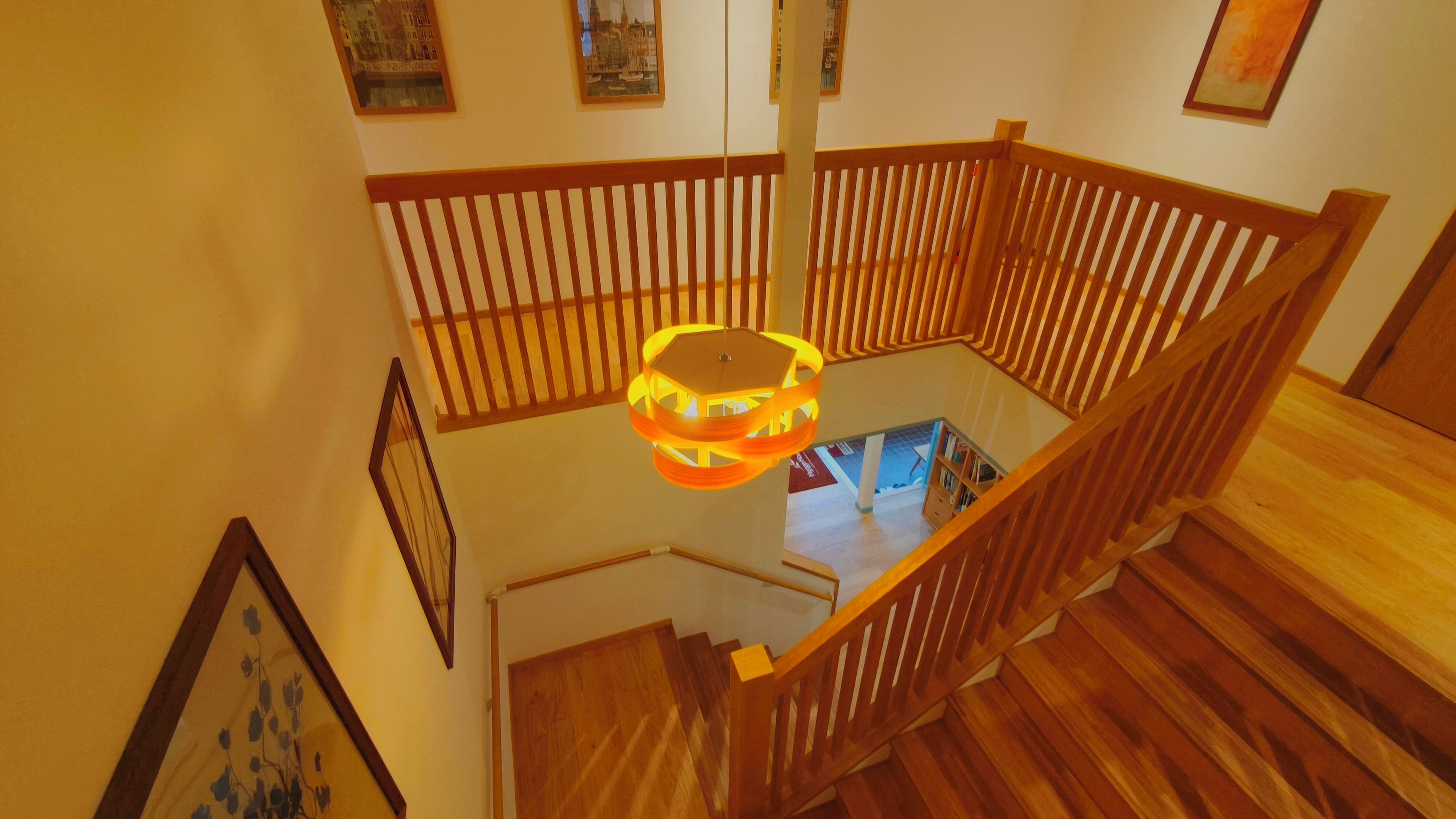 A wooden staircase with a hexagonal hanging light fixture.