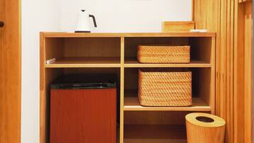A wooden cabinet with open shelves, a small appliance, and a trash bin.