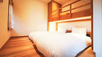 A bedroom with a wooden floor, a bed with white bedding, and a wooden headboard.