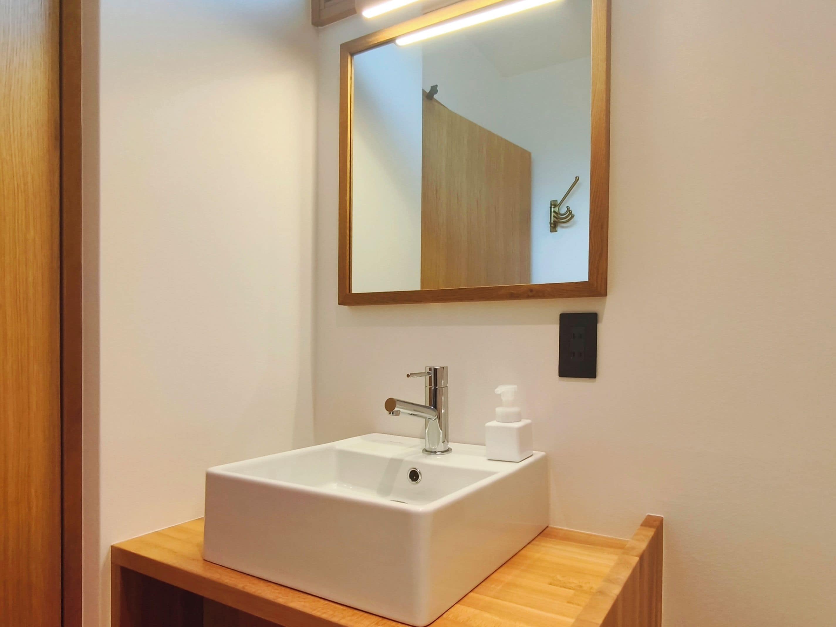A bathroom with a white sink, a mirror, and a wooden vanity.