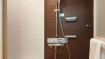 A bathroom with a wooden door, a shower with a handheld showerhead, and a towel rack.