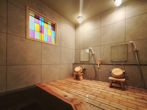 A bathroom with a wooden floor, a mirror, and a shower area.