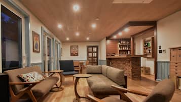A cozy living area with a fireplace, seating, and a bar with shelves.