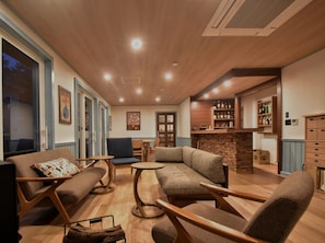 A cozy living area with a fireplace, seating, and a bar with shelves.