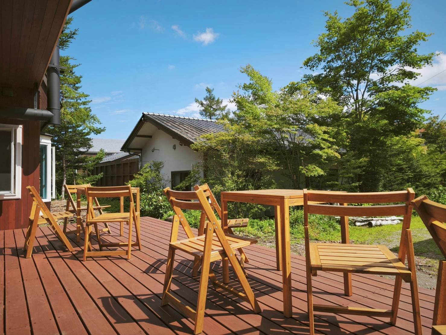 A wooden deck with outdoor seating and a building in the background.