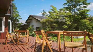 A wooden deck with outdoor seating and a building in the background.