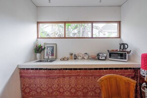 Una cocina compacta con ventana, un lavamanos, un microondas y un tostador.