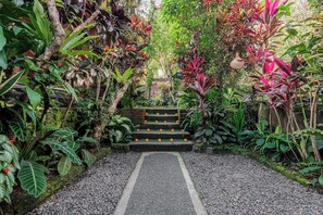 A garden pathway leading to a staircase surrounded by lush greenery and tropical plants. - Pondok Alami Villas 5BR & Pool (Ubud)