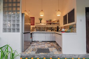Una cocina con piso de baldosas estampadas, lámparas colgantes y varios utensilios de cocina sobre la encimera.