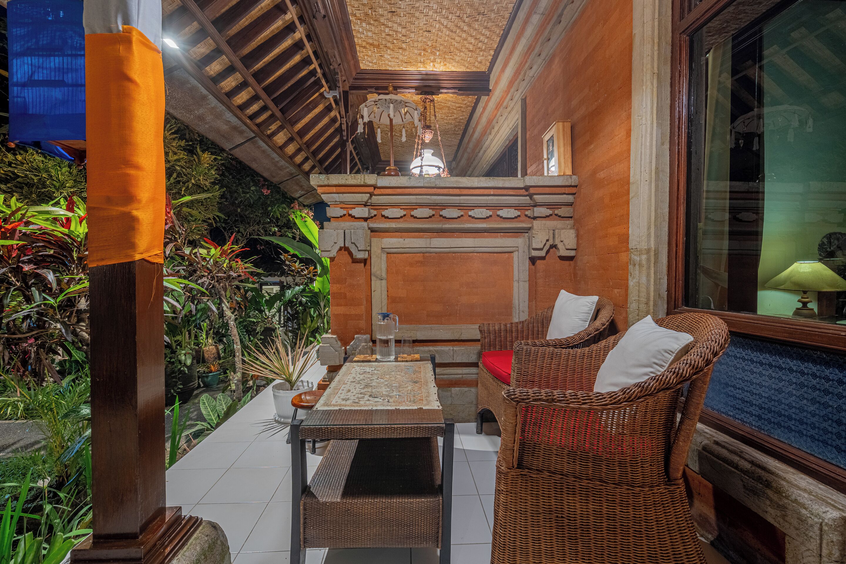Un espacio al aire libre acogedor con mobiliario de mimbre, suelo de baldosas y un techo decorativo.