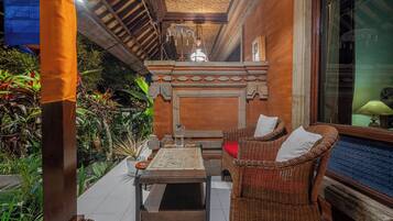 Un espacio al aire libre acogedor con mobiliario de mimbre, suelo de baldosas y un techo decorativo.
