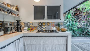 Una cocina con estufa integrada, cafetera y frutero sobre la encimera.