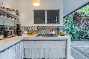 A kitchen with a built-in stove, a coffee maker, and a fruit bowl on the counter. - Pondok Alami Villas 5BR & Pool (Ubud)
