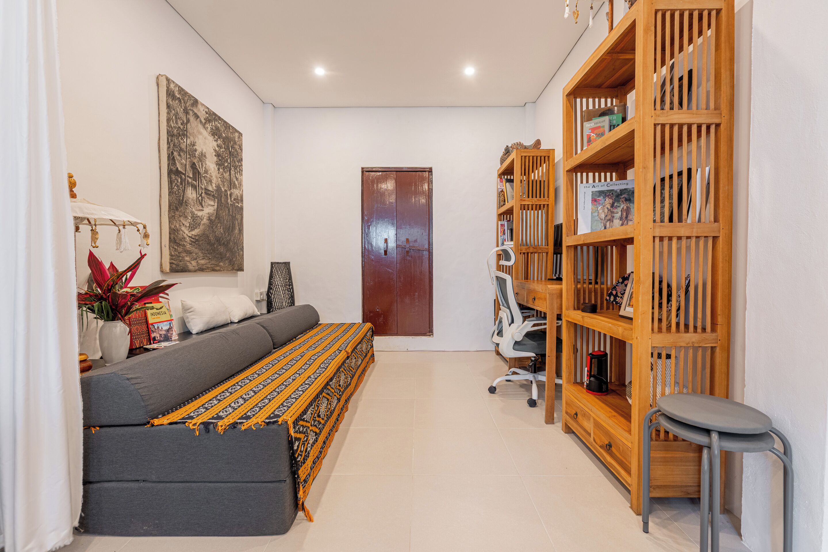 Una sala moderna con un sofá, una estantería, un cuadro y una puerta.