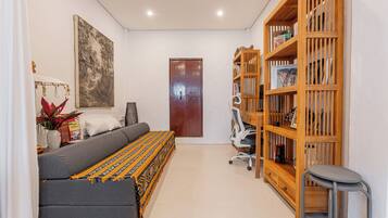 Una sala moderna con un sofá, una estantería, un cuadro y una puerta.