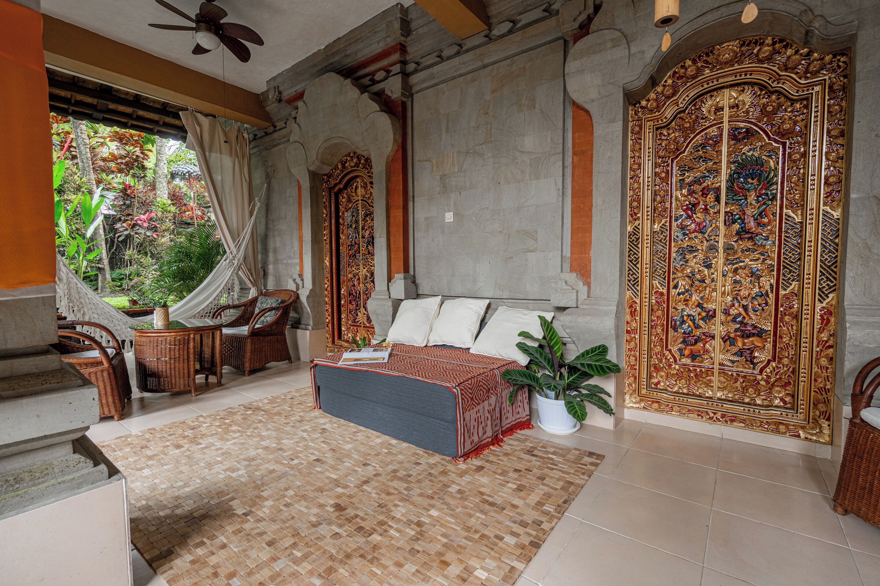 Una habitación con cama, una zona de lectura con una silla y una mesa, y una puerta grande y decorada.