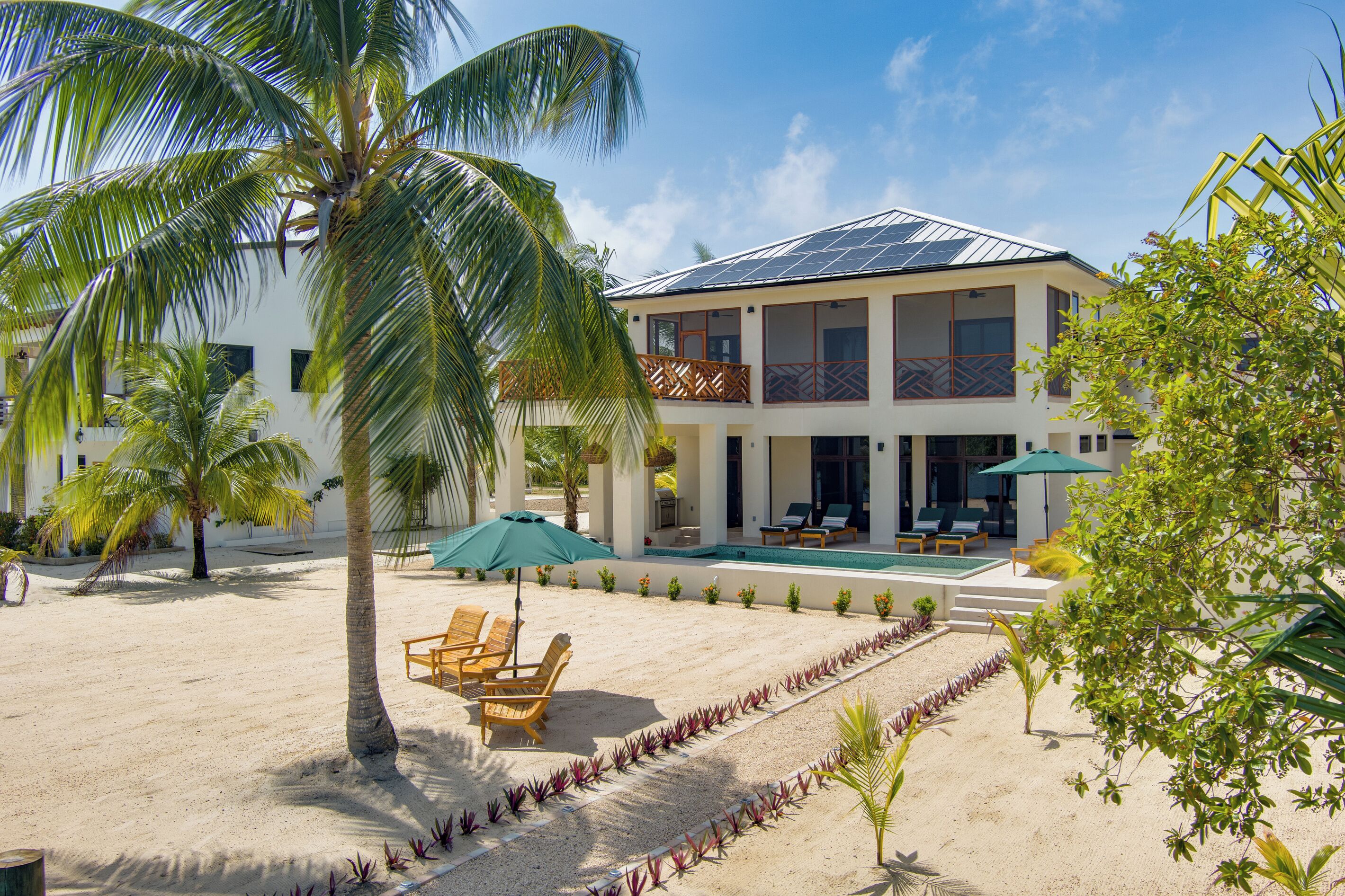Une propriété située en bord de mer, dotée d’une piscine, de chaises longues et d’un bâtiment à deux étages.